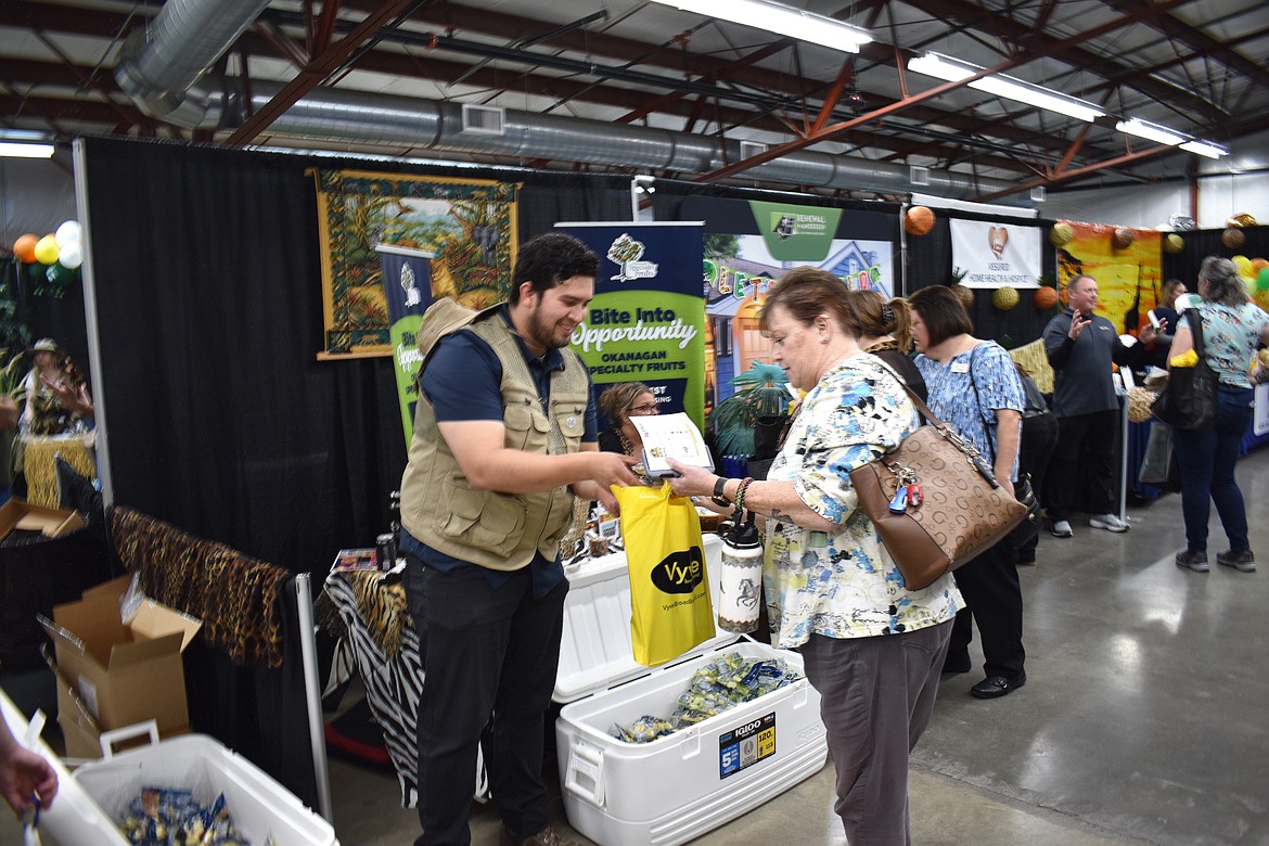 Pedro Barreras, safety coordinator for Okanagan Specialty Fruits, gives a packet of apples to Laura Silvers of Avamere at the Moses Lake Chamber of Commerce’s Business Expo Tuesday.