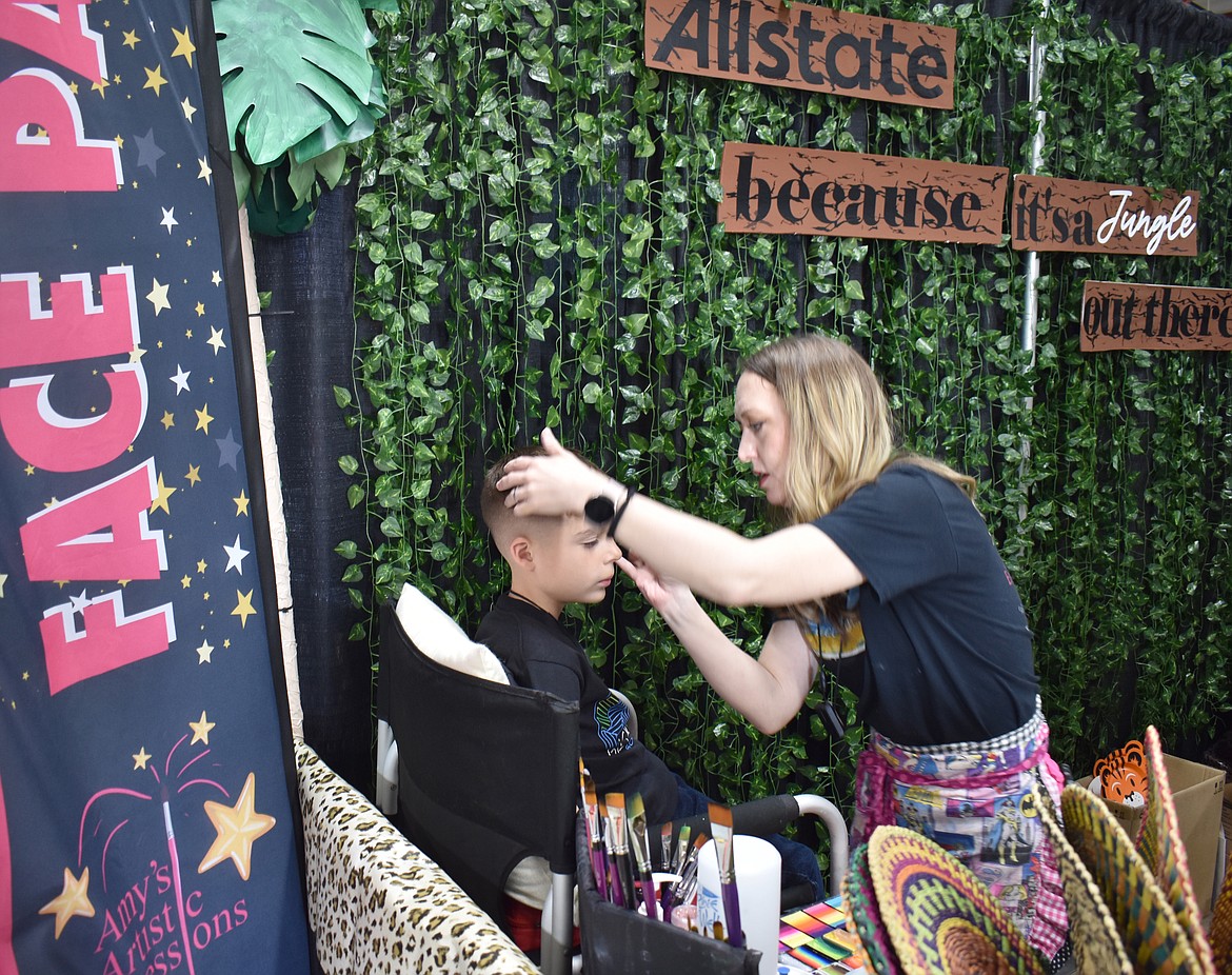 Alicia Lundquist of Amy’s Artistic Expressions paints the face of 9-year-old Santino Alejo at the Moses Lake Business Expo Tuesday.