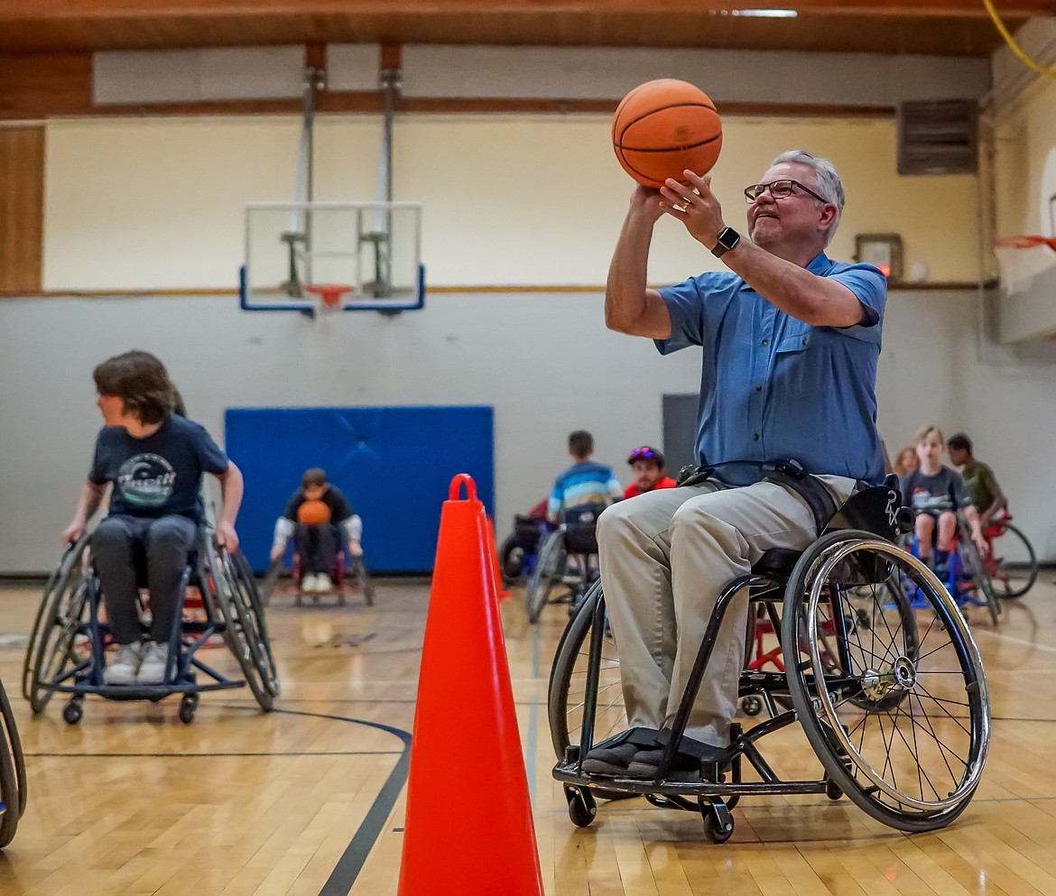Lake City Academy Principal Doug Zimmerman sits in a wheelchair and hones his shooting skills during a Parasport Spokane demonstration at Lake City Academy Tuesday afternoon.