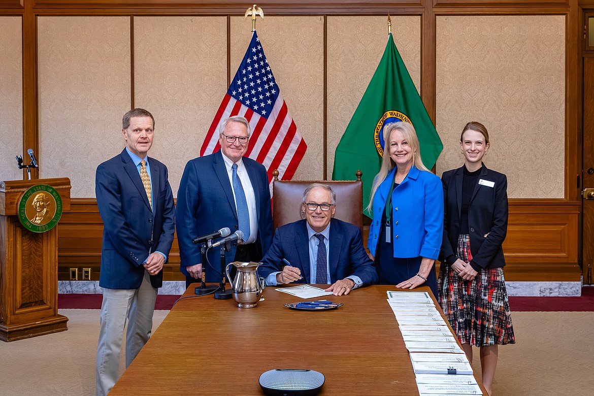 Gov. Jay Inslee, sitting, signs House Bill 1752, which authorizes the U.S. Bureau of Reclamation to apply for and obtain approval for water right modifications.