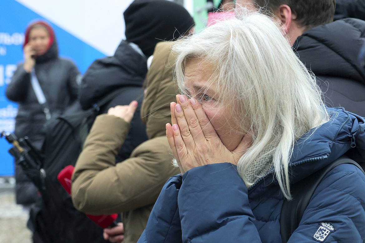 A woman reacts as she place flowers by the fence next to the Crocus City Hall, on the western edge of Moscow, Russia, Saturday, March 23, 2024, following an attack Friday, for which the Islamic State group claimed responsibility. Russian officials say more than 90 people have been killed by assailants who burst into a concert hall and sprayed the crowd with gunfire. (AP Photo/Vitaly Smolnikov)