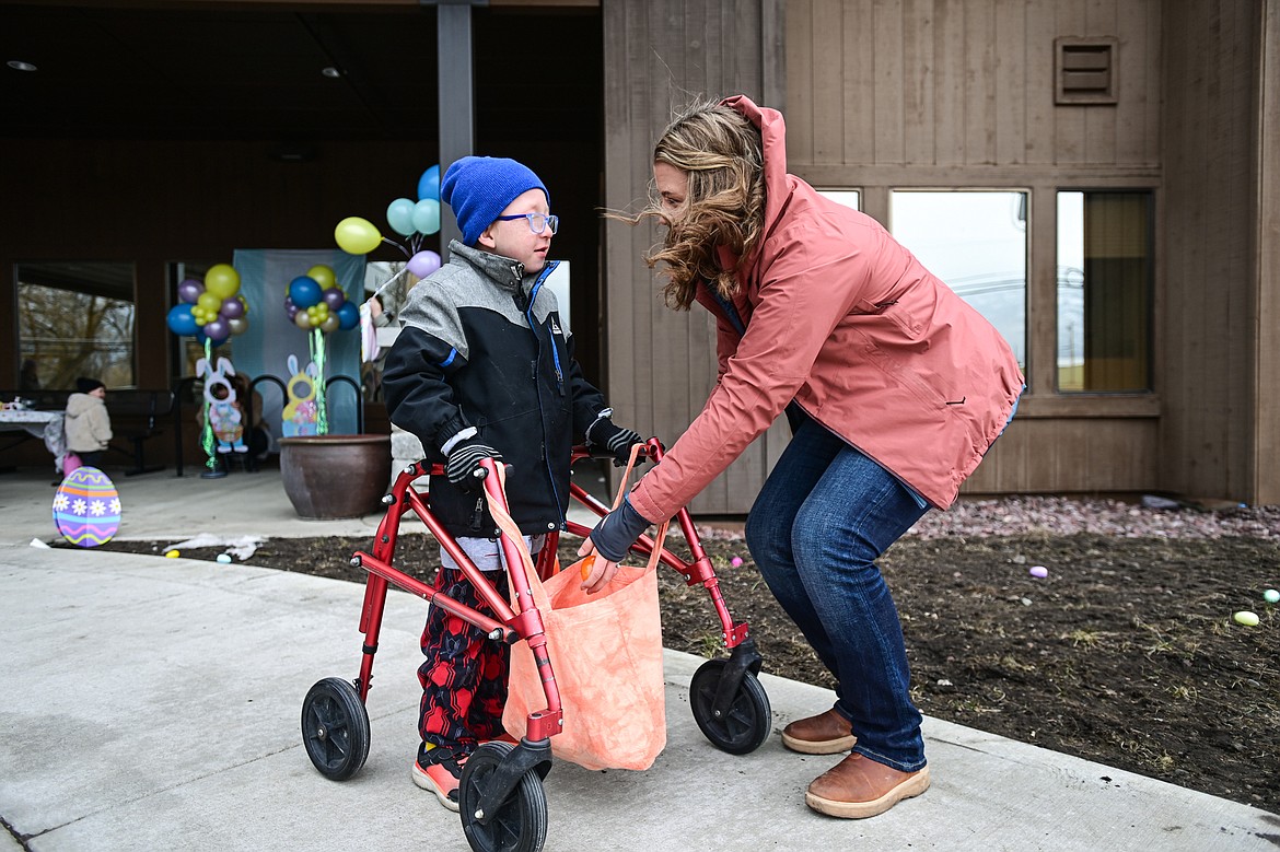 Jenni Kingan, owner of Healthy Beginnings Physical Therapy, helps a child pick up eggs during an Inclusive Easter Egg Hunt for kids with low vision, sensory or wheelchair and walker accessibility needs hosted by Healthy Beginnings Pediatric Therapy in Columbia Falls on Saturday, March 23. (Casey Kreider/Daily Inter Lake)