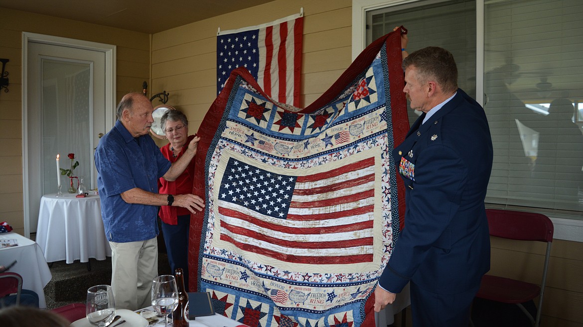 Giannine O'Connor presented Joel Walker with his Quilt of Valor. Walker and his son-in-law, Michael Hinz, hold up the completed quilt to show O'Connor's hard work to those in attendance.