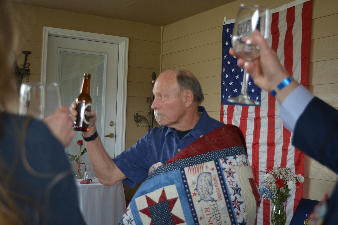 Joel Walker raises his beer, wrapped in his new Quilt of Valor.