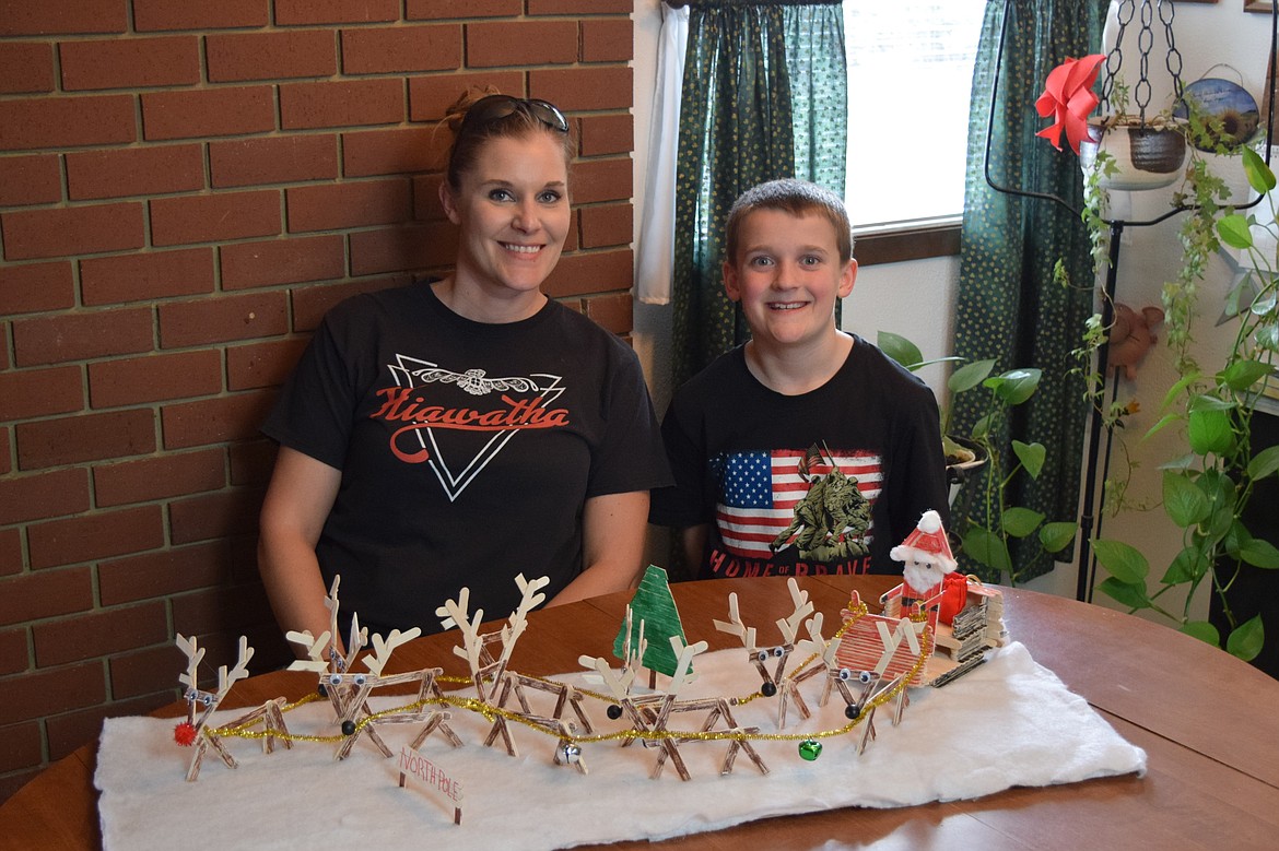 Othello resident Casie Hampton, left, and her son Logan Hampton, right, sit behind Logan Hampton’s popsicle stick depiction of Santa and his reindeer, which was one of 40 national winners of the Popsicle Stick with Art! contest.