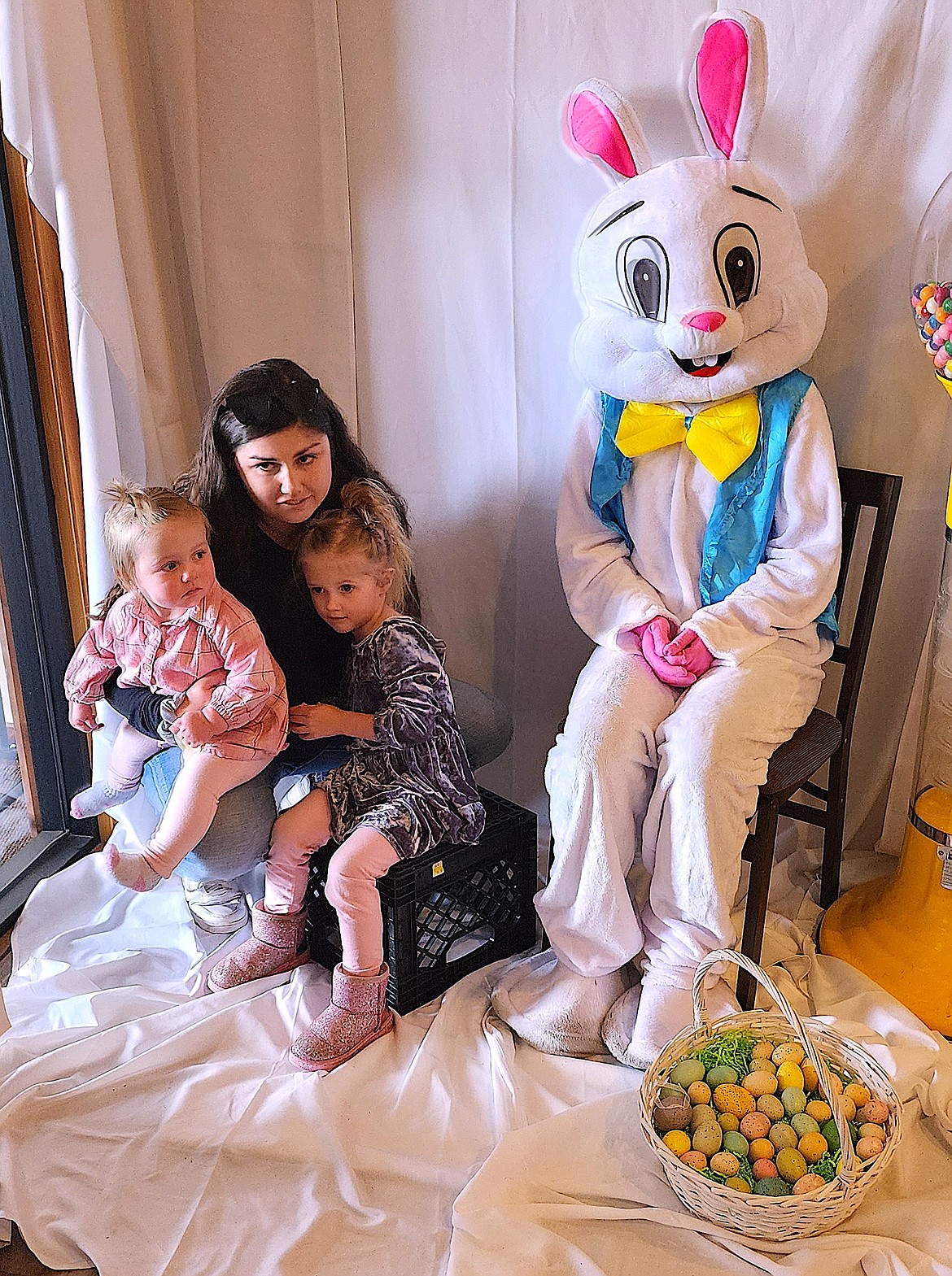 Mariah Delaney holds daughters Madison, left, and Brynlee as they sit by the Easter Bunny at the Easter Bazaar and Easter Egg Hunt at Ninepipes Lodge on Sunday/ (Berl Tiskus/Leader)