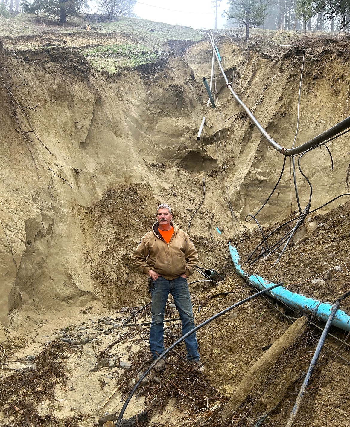 John Nelson, Moyie Springs Public Works Supervisor, stands in the newly formed trench where the city's main water line broke on Sunday.