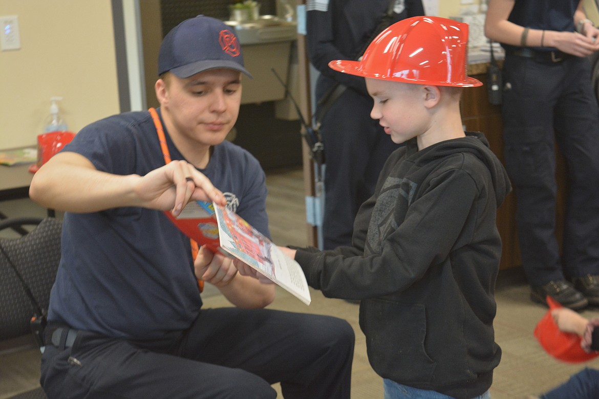 Probationary firefighter Cooper Walk shows Sawyer Murrell some of the equipment firefighters use during a field trip for Silver Hills Elementary School students.