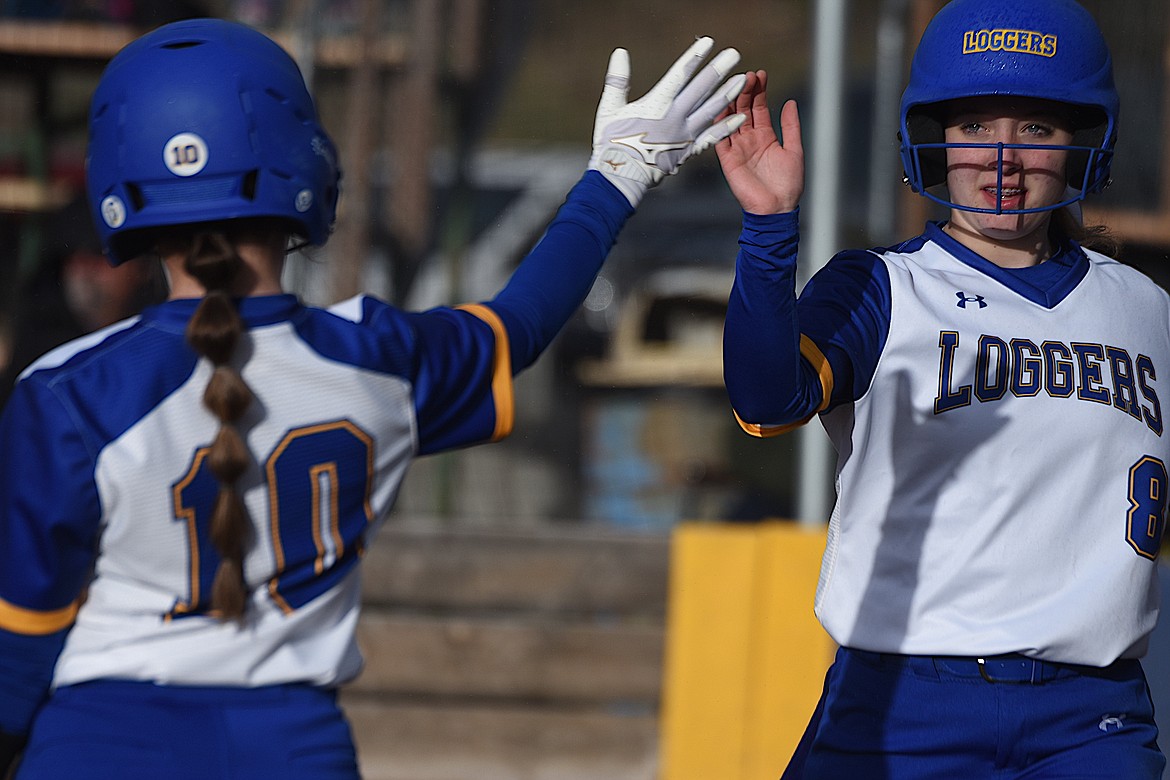 Libby's Dakota Allen (8) is congratulated by teammate Madison Vincent (10) on Thursday, March 28, after scoring a run against Eureka at Remp Field in Libby. The Loggers won 12-2 in six innings. (Scott Shindledecker/The Western News)