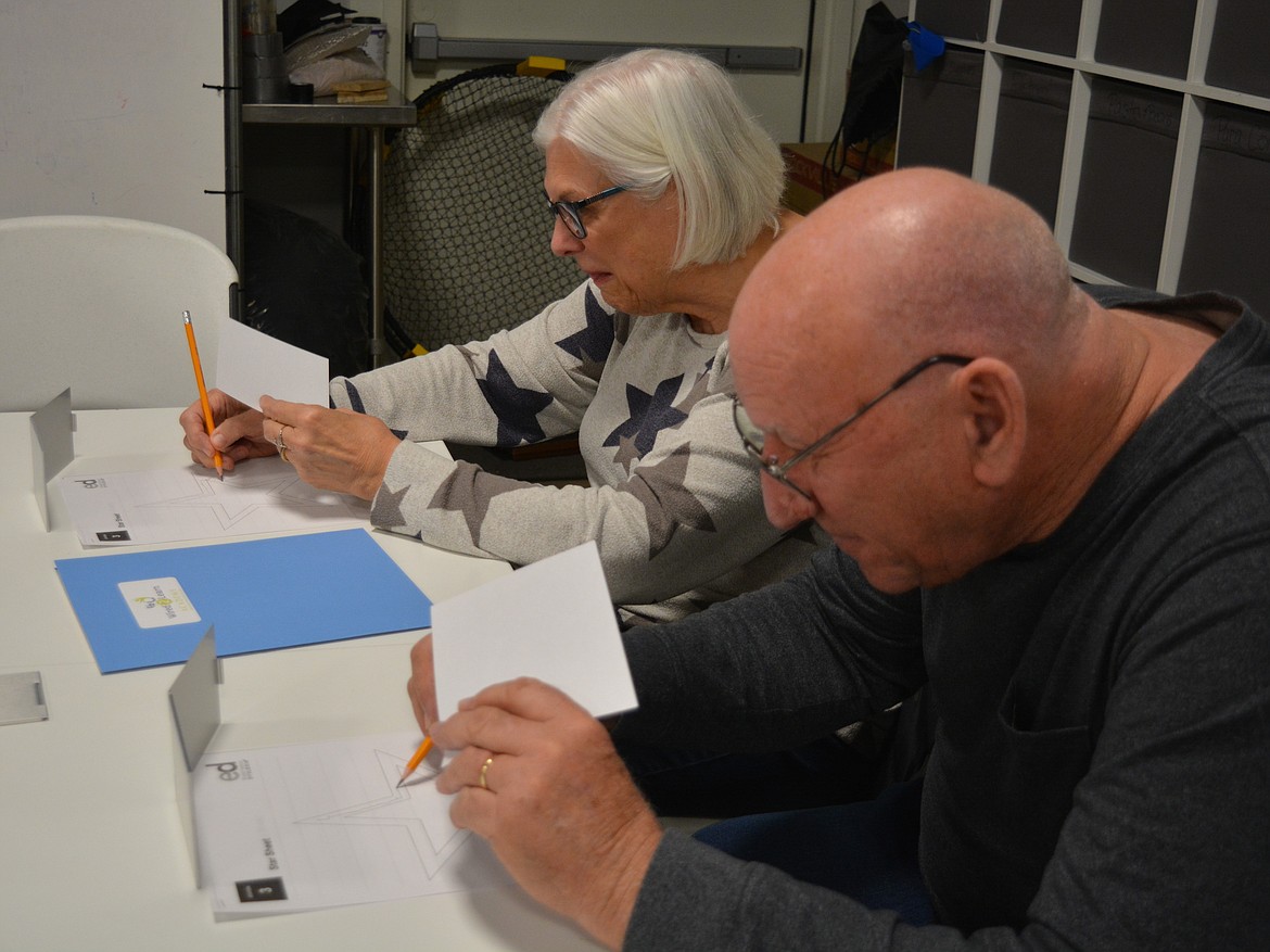 Cindy and David Bessey try to draw a star shape while covering the paper from view and using a mirror. The exercise was part of a dyslexia simulation.