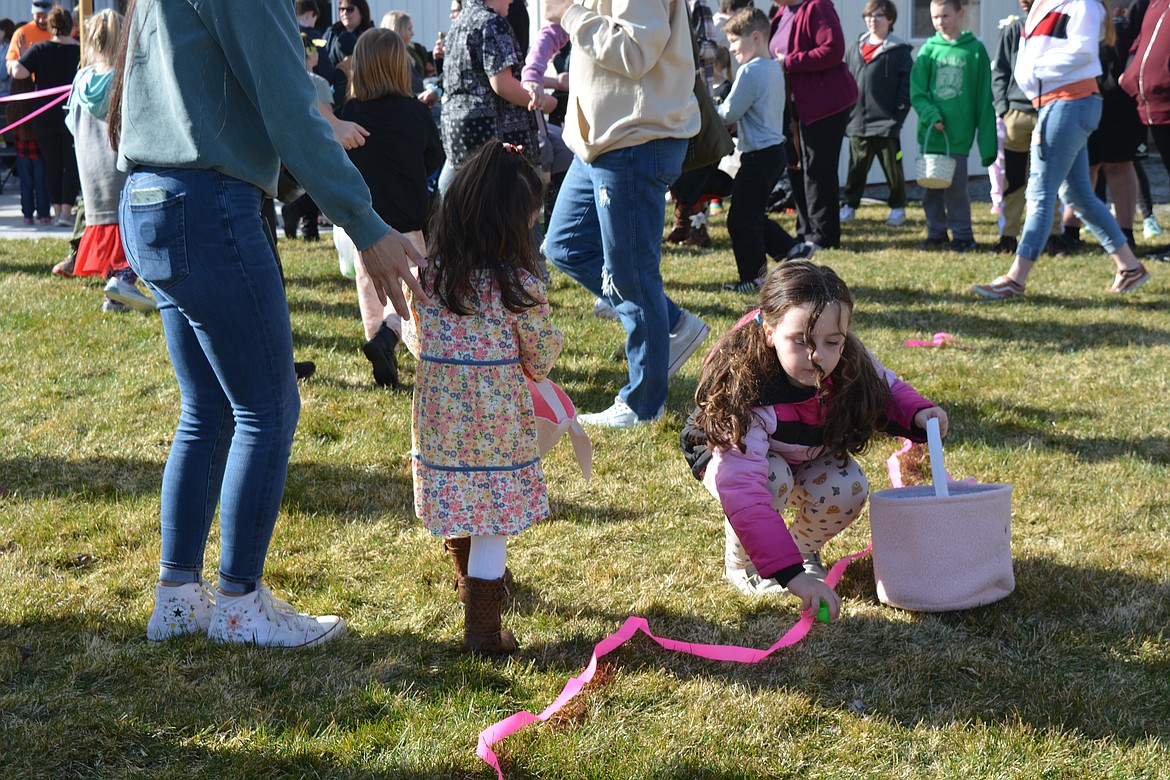 A little girl finds an unoccupied place on the lawn to retrieve eggs during an Easter egg hunt.