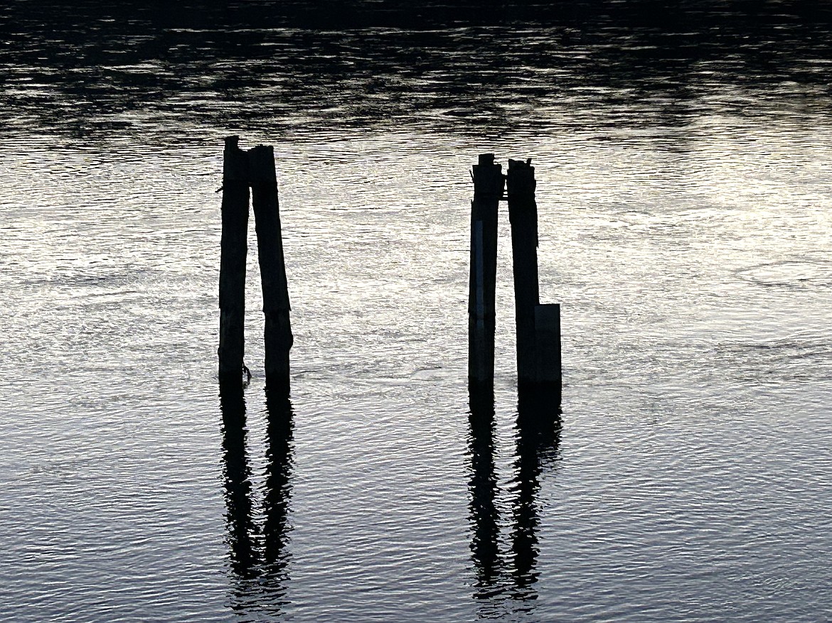 The shimmering waters of the Spokane River flow past posts on a recent evening.