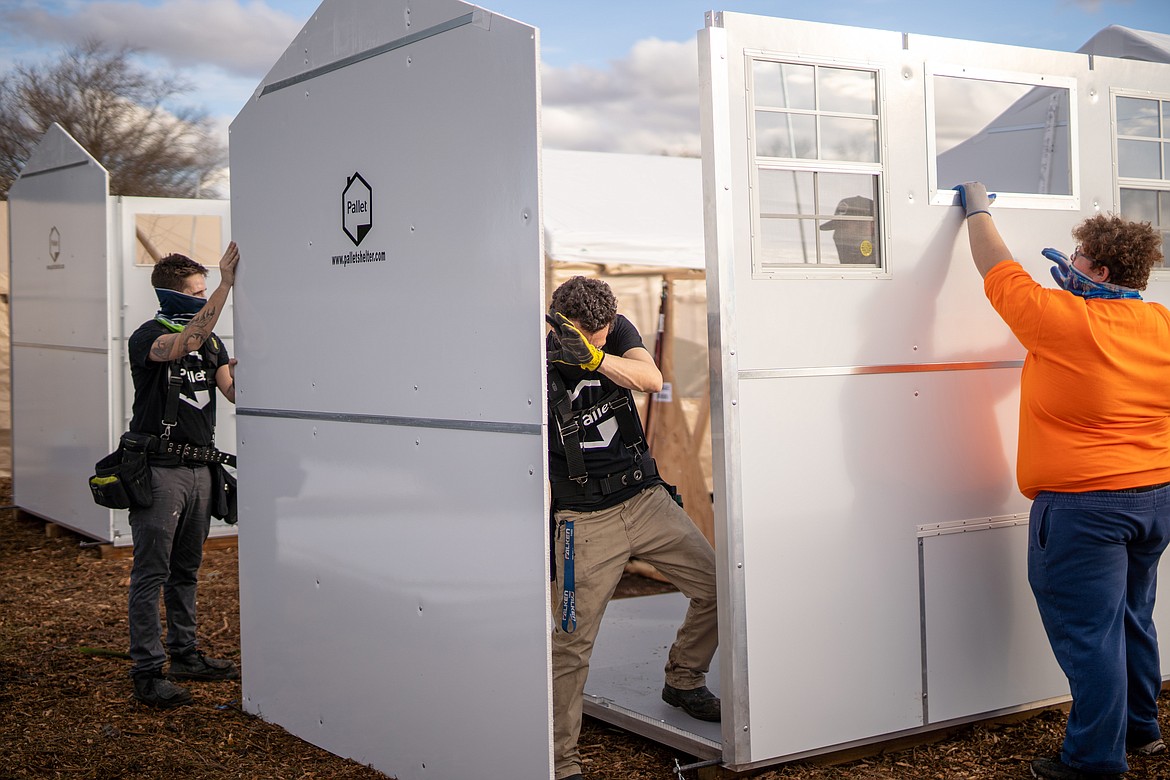 Workers assemble temporary dwellings at a Pallet Shelter village. The city of Moses Lake has ordered 40 of the 64-square-foot structures, which can be assembled in less than an hour.