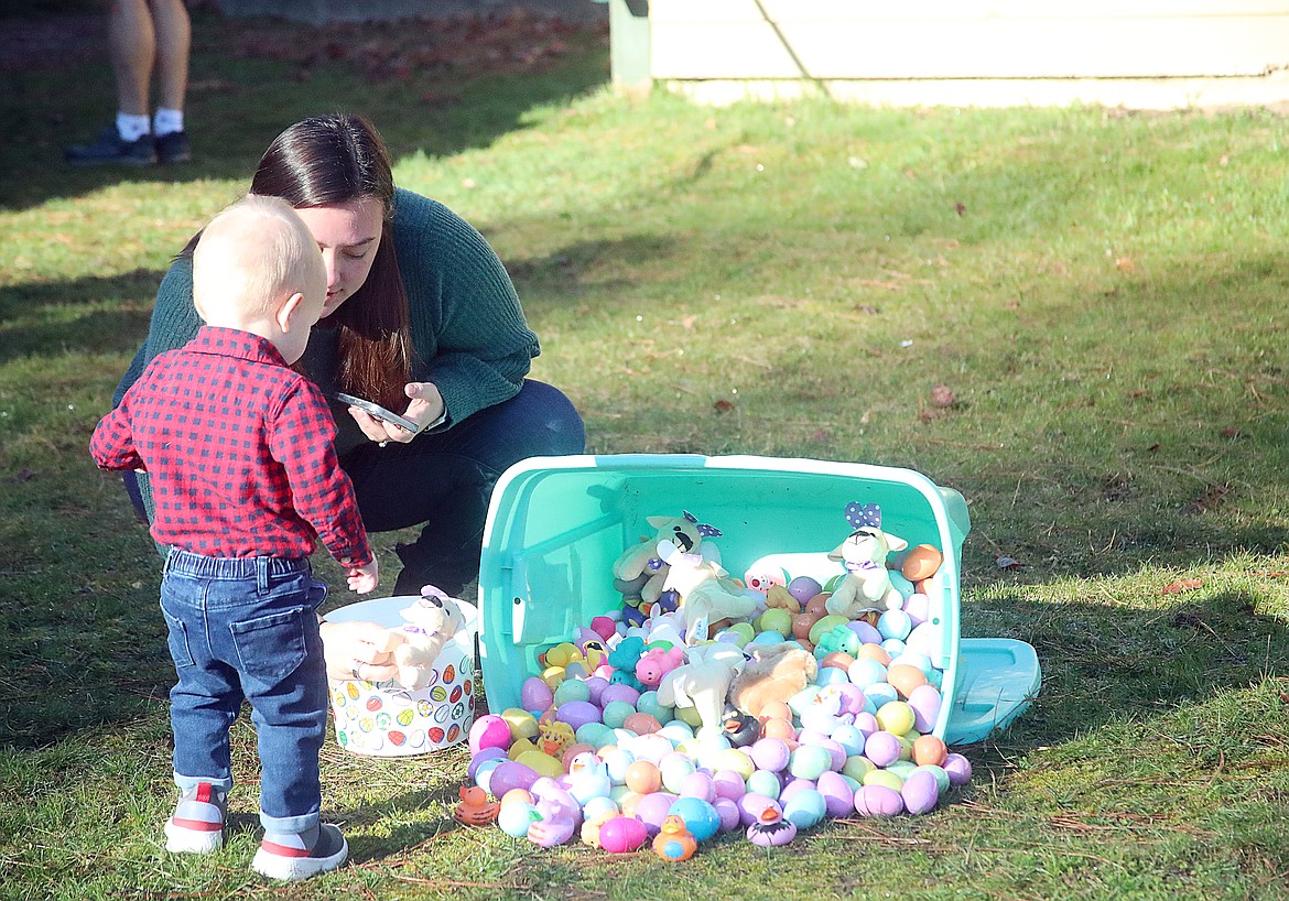 A young toddler gets some help finding a few eggs at the "crawlers" area. While eggs for older youth were scattered around a specified area, the eggs for the youngest youth were left near the tote due to the wet grass.