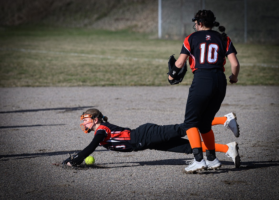 Plains pitcher Tia Bellinger dives for a ball under the watchful eye of teammate Randie Kilgore during their game this past week versus Thompson Falls in Plains. (Photo by Tracy Scott)