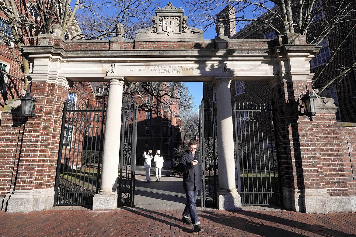 A passer-by walks through a gate to the Harvard University campus, Jan. 2, 2024, in Cambridge, Mass. As more than 2 million graduating high school students from across the United States finalize their decisions on what college to attend this fall, many are facing jaw-dropping costs — in some cases, as much as $95,000. (AP Photo/Steven Senne, File)