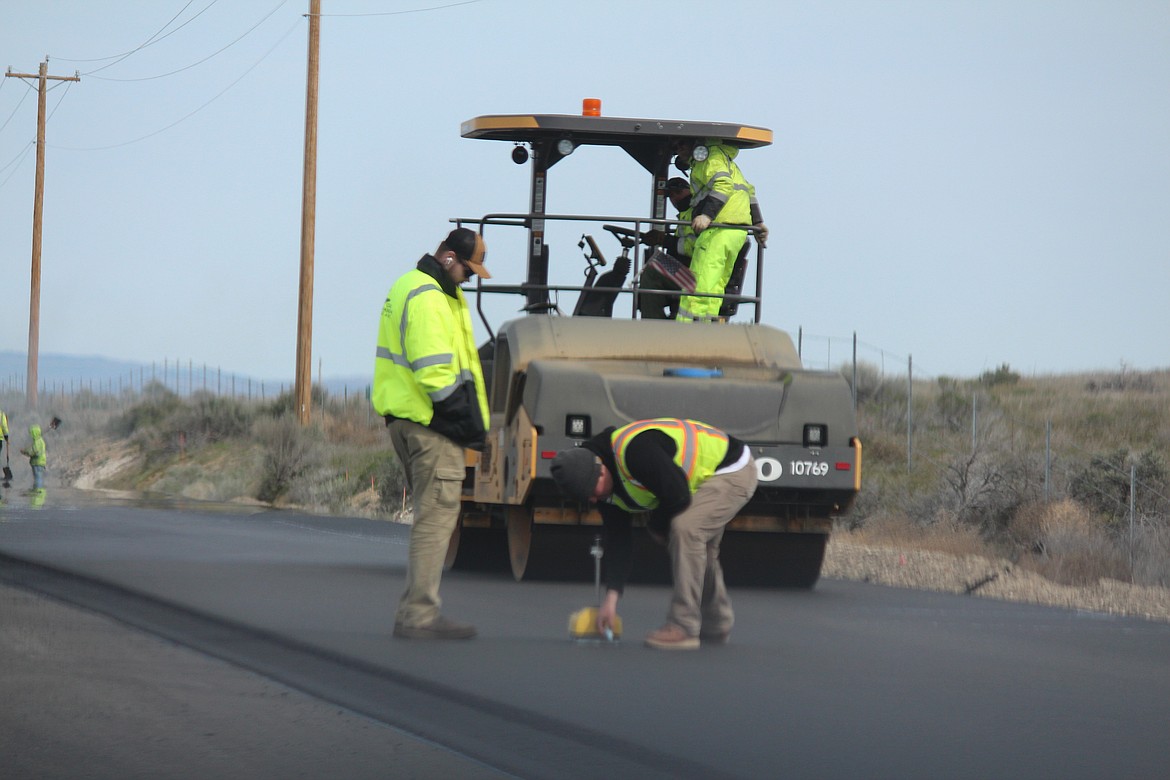 Workers check the depth of new asphalt along Silica Road. The road is getting widened and paved as part of a larger project to improve traffic flow around the Gorge Amphitheater.