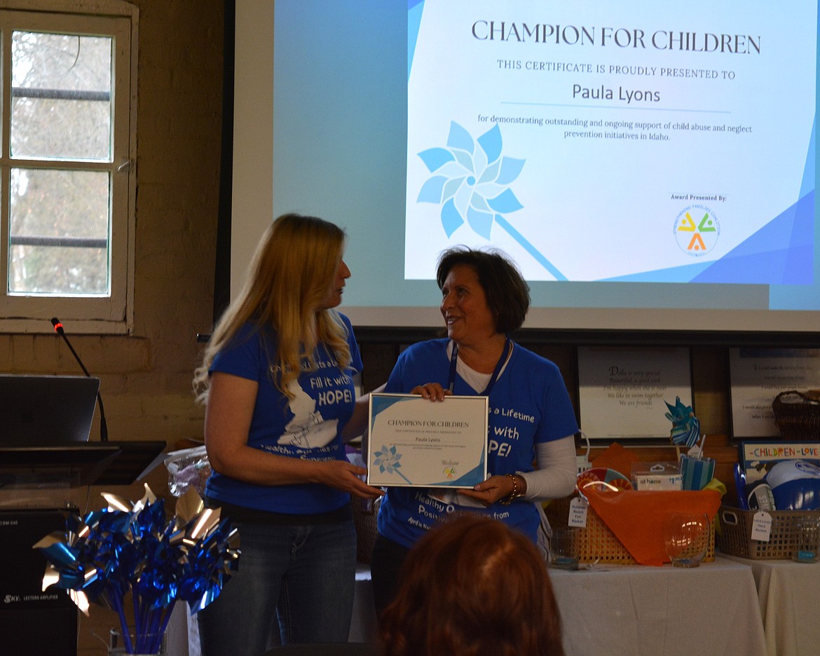 Paula Lyon receives the Champion For Children Award from Kaylynn Augh at a child abuse prevention event Thursday at the Human Rights Education Institute.