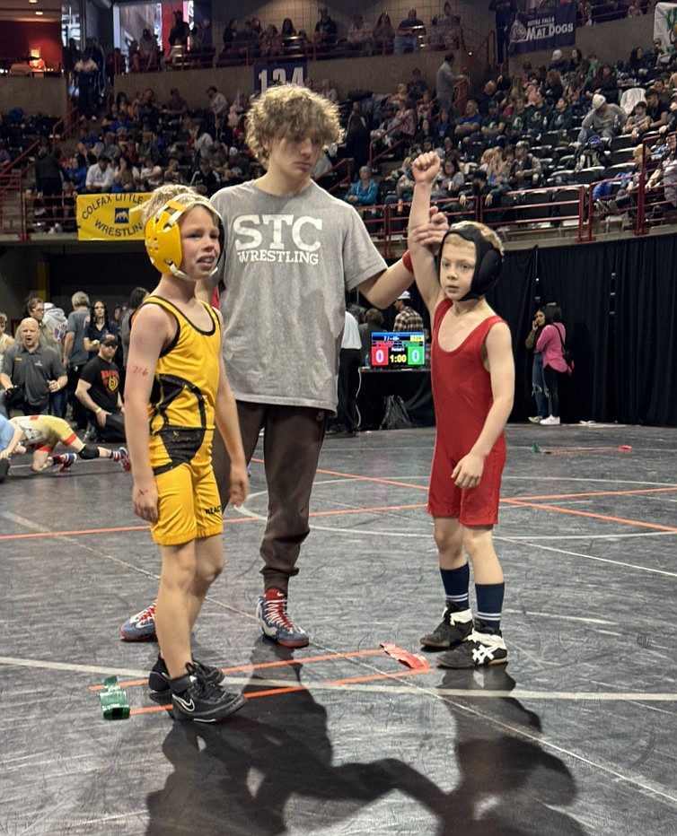 Cody Moren has his hand raised by an official after winning a match.