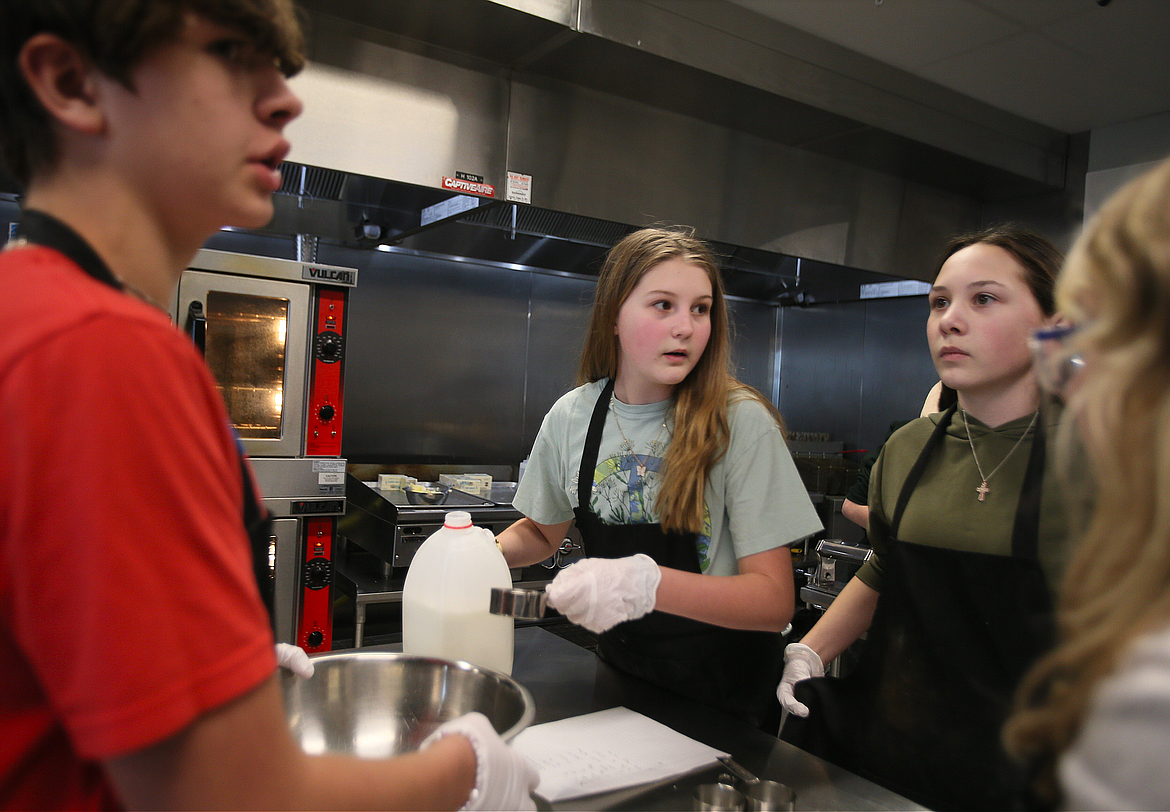 Seventh grader Scarlytte Erickson, center, prepares to measure milk for a recipe at Elevate Academy North in Post Falls. Also pictured: Titus Fife, left and Lillia Kenney, right.