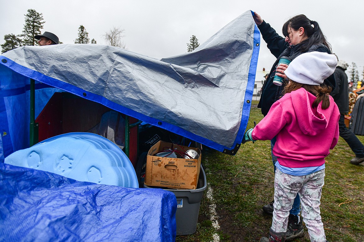 Visitors look at items under tarps to protect them from the rain at the 58th annual Creston Auction and Country Fair on Saturday, April 6. The event is the largest fundraiser for the Creston Fire Department and has been held since 1966. (Casey Kreider/Daily Inter Lake)