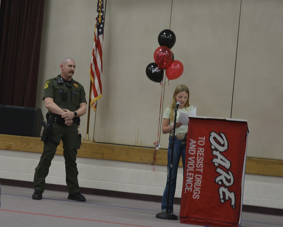 Fifth-grader Kinley McMurray reads her D.A.R.E. essay during a graduation ceremony at Garwood Elementary School as deputy Brett Clauson listens.