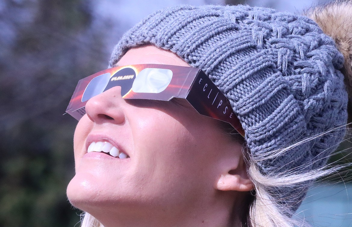 Nichelle Holmes uses special glasses to view the partial solar eclipse from the waterfront in downtown Coeur d'Alene Monday morning.