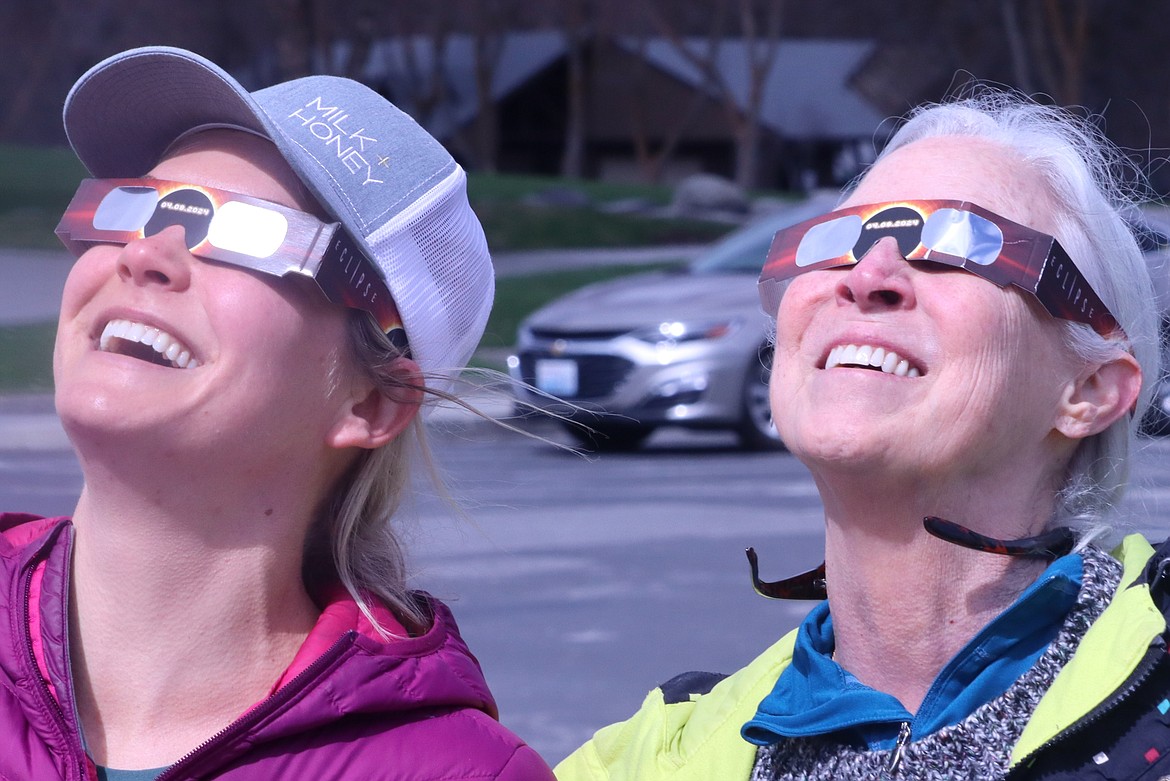 Friends Holly Lehrman, left, and Maggie Bennett take in the partial solar eclipse in Coeur d'Alene on Monday morning.