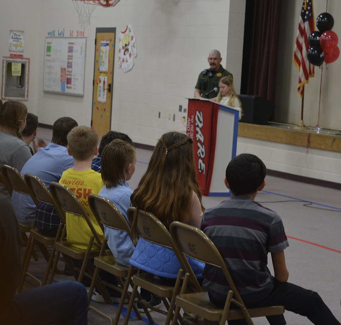 Elliot Baune reads her essay near deputy Brett Clauson at Garwood Elementary's D.A.R.E. graduation ceremony.