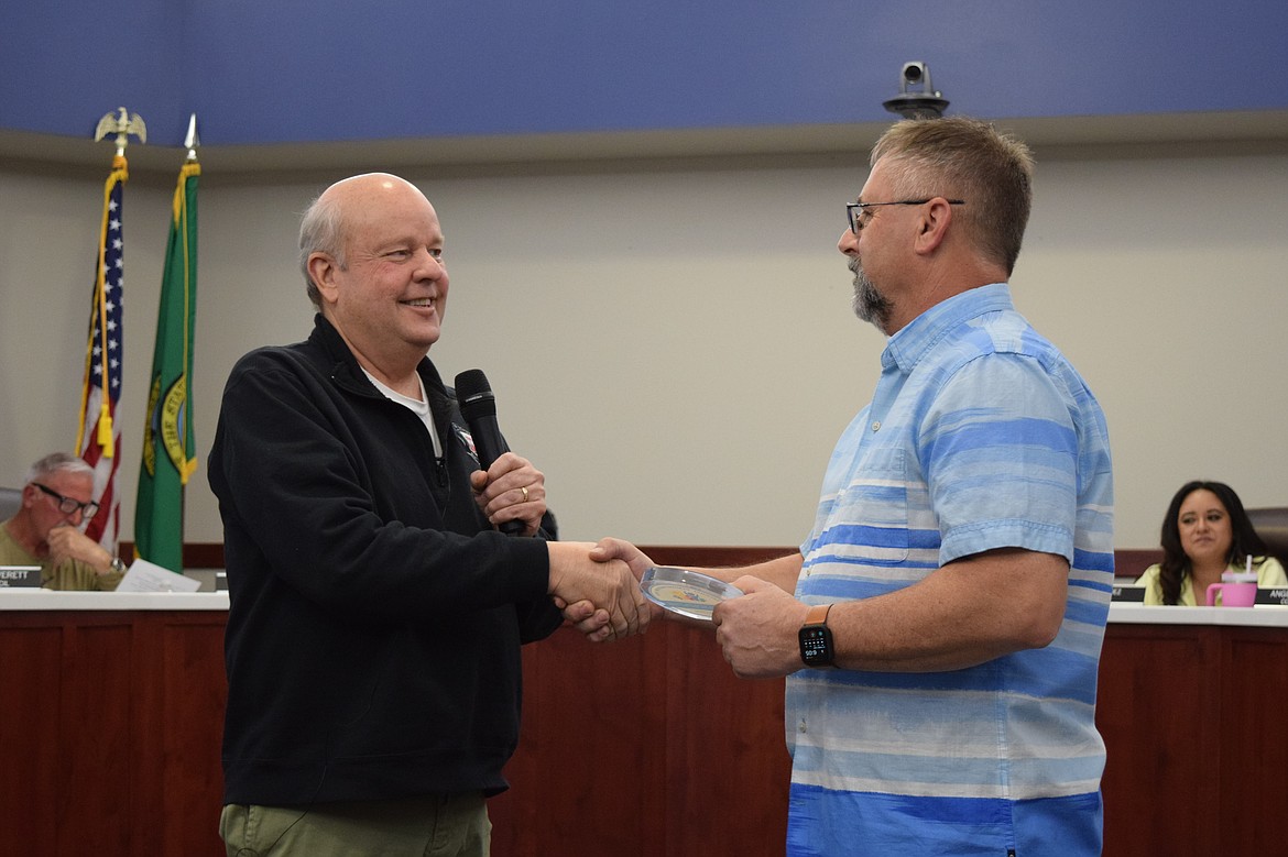 Othello Mayor Shawn Logan, left, presents the PlayCore award designating Othello’s Iron Horse Playground as a National Demonstration Site to Othello Public Works Director Curt Carpenter, right, during Monday’s Othello City Council meeting.