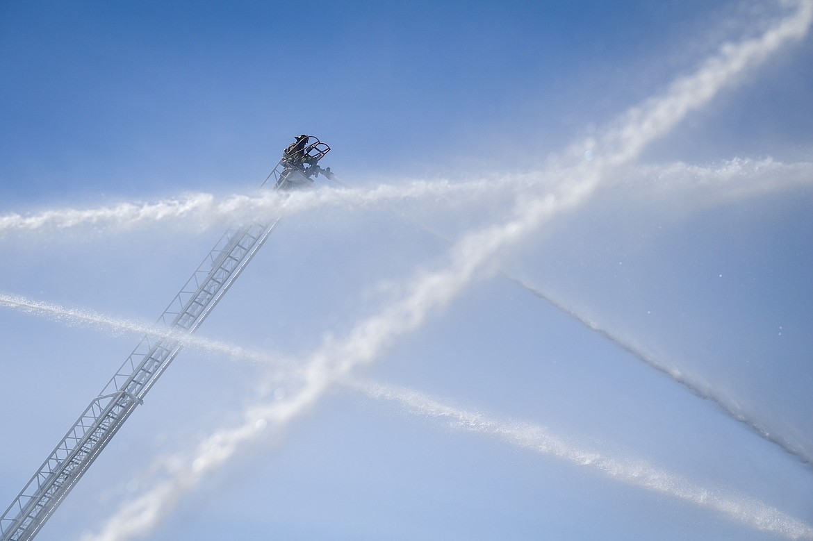 A firefighter on an aerial ladder mans a hose as streams of water from other units attack a fire at the Quality Inn on U.S. Highway 2 West in Kalispell on Wednesday, April 10. (Casey Kreider/Daily Inter Lake)