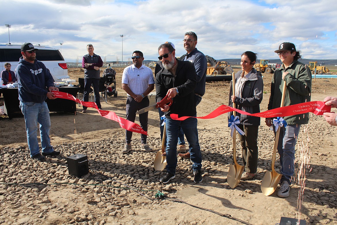 With the help of the Quincy Valley Chamber of Commerce and surrounded by family and industry partners, Angel Garza, center, initiates the Jackrabbit Estates project by cutting the ribbon.