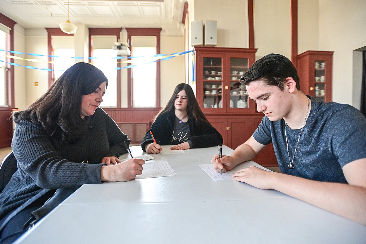 Kathryn, Elise and Sam Harvey write essays on "What it's like being you" to be included in a time capsule during Central School's 130th anniversary party at the Northwest Montana History Museum on Friday, April 12. (Casey Kreider/Daily Inter Lake)