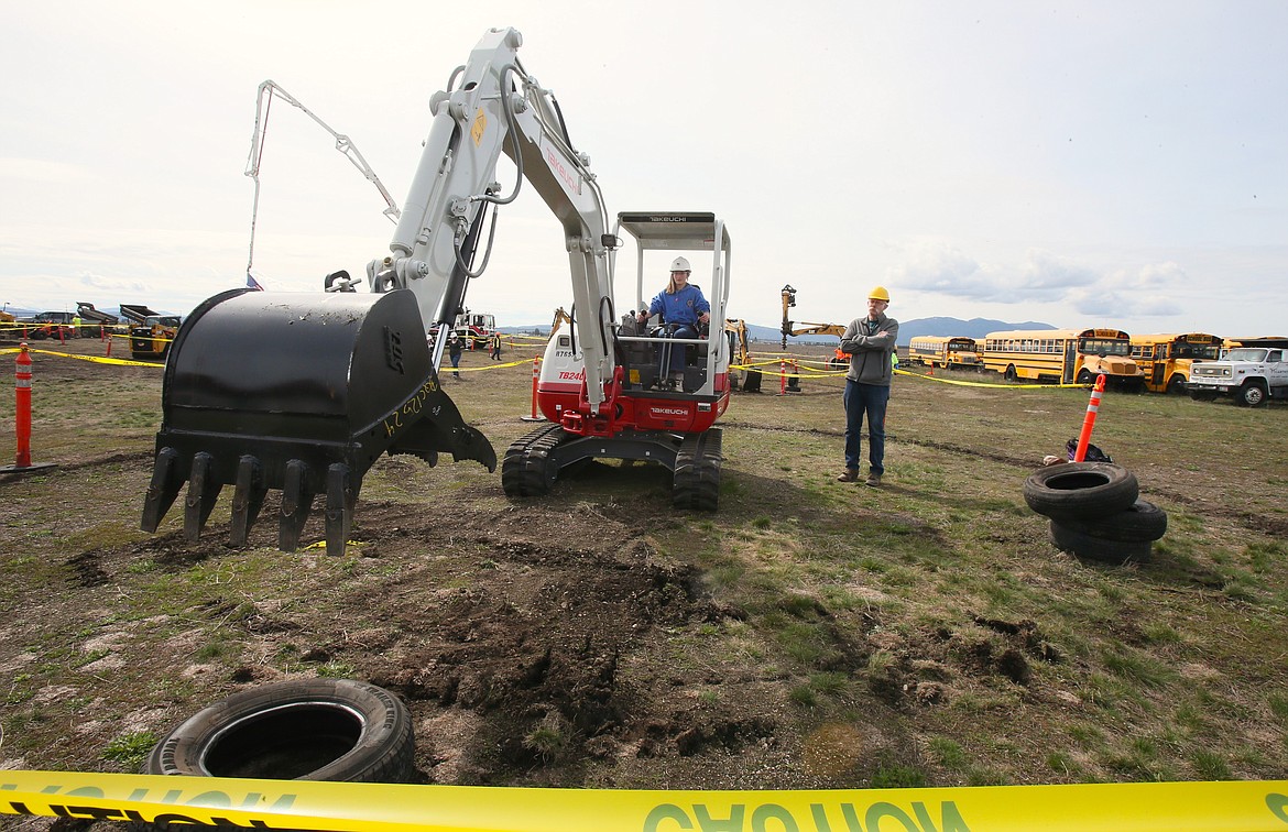 Lake City High School sophomore Xanaia Dahlstrom runs a mini excavator Friday morning assisted by retired construction worker Jim Sieck during the annual Hard Hats, Hammers and Hot Dogs skilled trades career day at the Kootenai Technical Education Campus in Rathdrum.