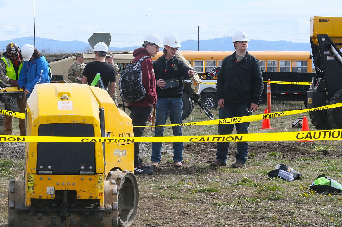 Coeur d'Alene High School freshman Daymian Reese, center, points as he controls a compactor Friday morning at the Hard Hats, Hammers and Hot Dogs event at KTEC. He is flanked by classmates Fynyx Workman, left, and Justin Gilmore.