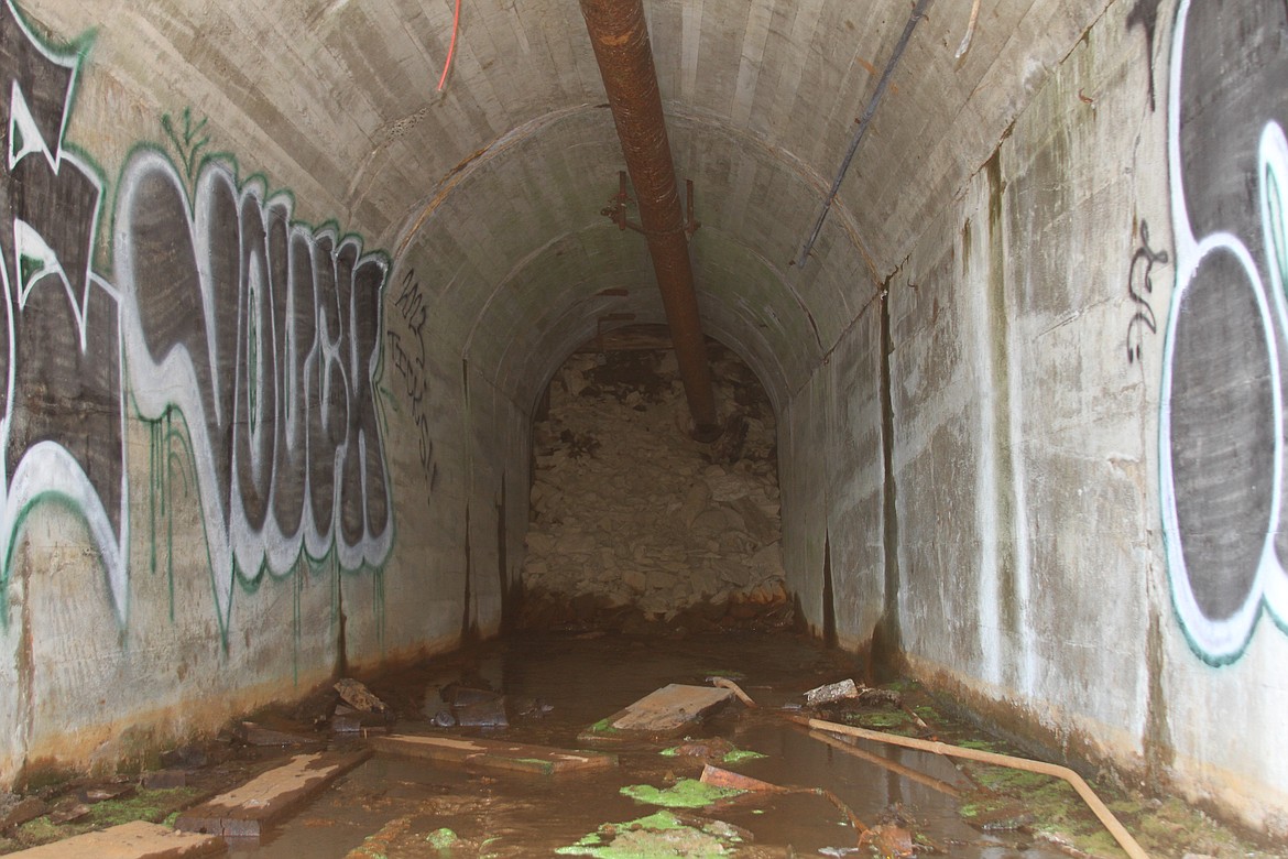 A peek behind the gate at the Tamarack shows the collapsed drift and steady flow of contaminated mine water.