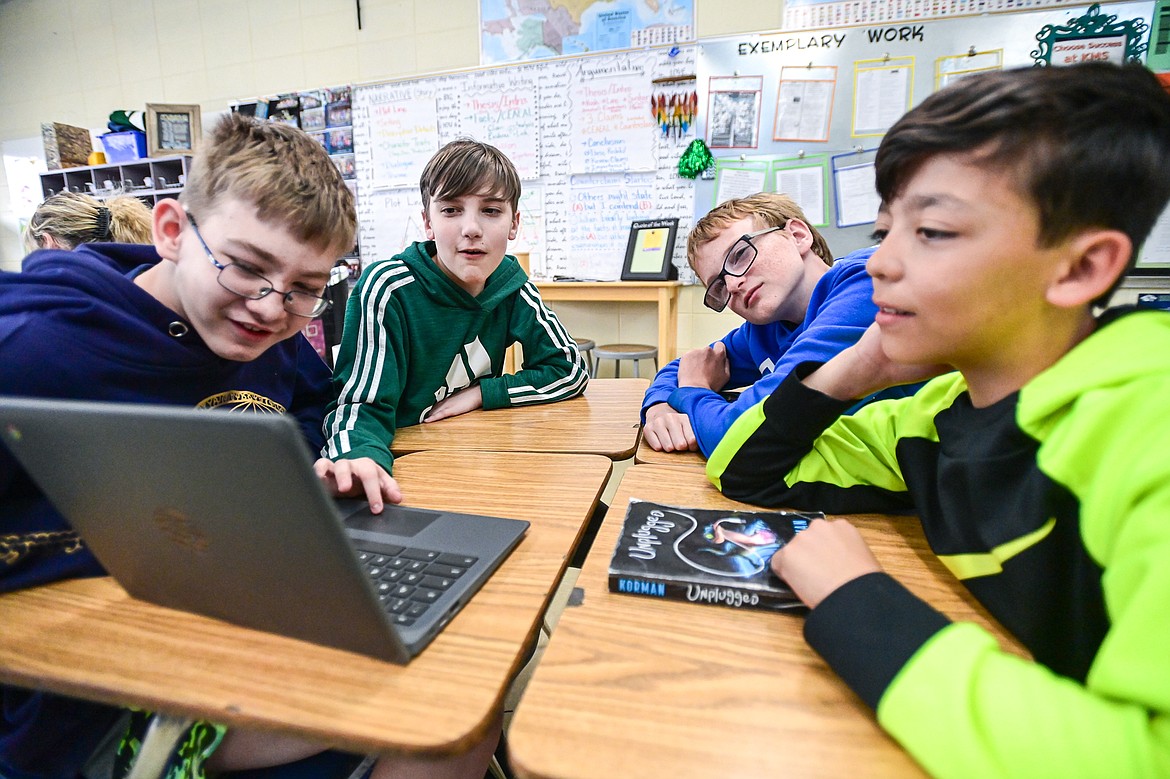 From left, Maxwell McMenamin, Levi Boone, Jared Kelly and Jeremiah Gardner read over their stories and illustrations created using artificial intelligence software in seventh-grade teacher Kristi Sanders' class at Kalispell Middle School on Tuesday, April 16. (Casey Kreider/Daily Inter Lake)