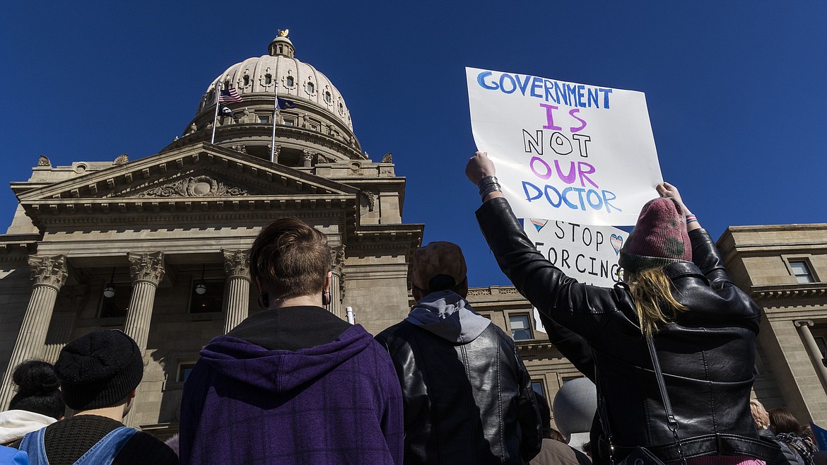 People gather in front of the Idaho Statehouse in opposition to anti-transgender legislation moving through an Idaho Republican congress, Friday, Feb. 24, 2023, in Boise, Idaho. The U.S. Supreme Court's decision on Monday, April 15, 2024, allows the state to put in place a 2023 law that subjects physicians to up to 10 years in prison if they provide hormones, puberty blockers or other gender-affirming care to people under age 18. A federal judge in Idaho had previously blocked the law in its entirety. (Darin Oswald/Idaho Statesman via AP, File)