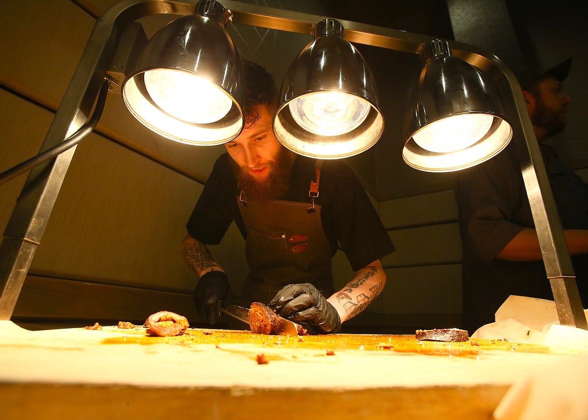 Chef James Seidler of Westwood Brewing Co. slices appetizers of beef flank steak with red pepper pesto and goat cheese Thursday during CDAIDE's Care Affair at The Coeur d'Alene Resort.