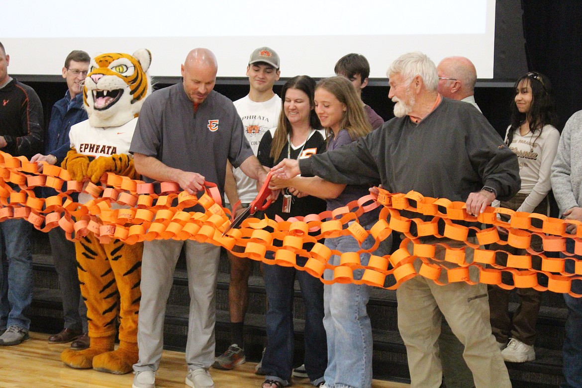 From left in foreground: Ephrata Schools Mascot Tao, Ephrata Assistant Superintendent Ken Murray, Ephrata Middle School Principal Tina Mullings, Erika Morford and former EMS Principal Pat Flannery cut the “ribbon” made up of an orange paper chain made by EMS students at an open house showing off the new EMS Monday.