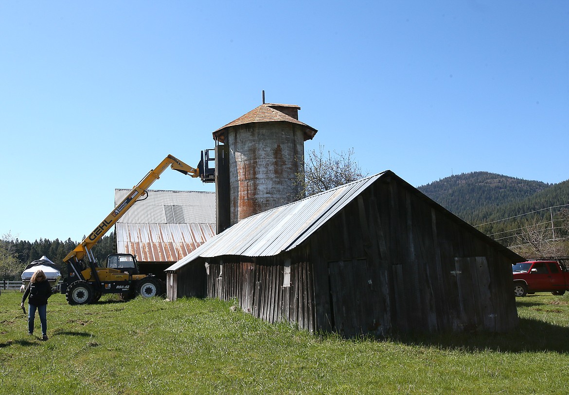 Susan Sloyka walks past the nearly 100-year-old grain silo and one of several outbuildings on her property Friday morning.