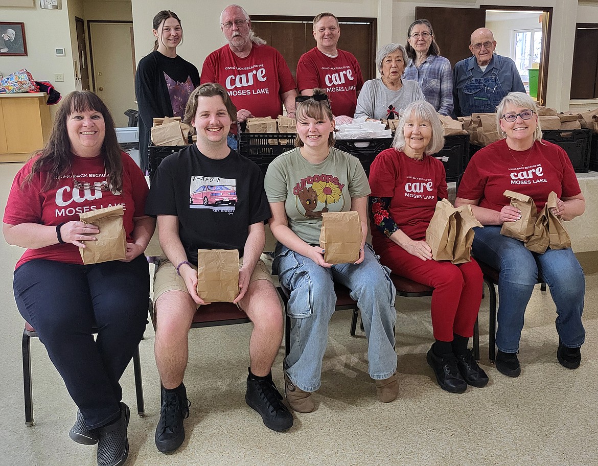 Members of Care Moses Lake, shown here holding the sack lunches the group makes for those who need them, were recognized by Serve Washington for their community work with the 2024 Washington State Volunteer Service Award.