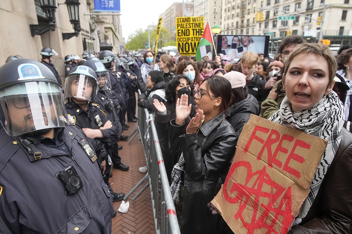 Police in Riot gear stand guard as demonstrators chant slogans outside the Columbia University campus, Thursday, April 18, 2024, in New York. U.S. colleges and universities are preparing for end-of-year commencement ceremonies with a unique challenge: providing safety for graduates while honoring the free speech rights of students involved in protests over the Israel-Hamas war. (AP Photo/Mary Altaffer, File)