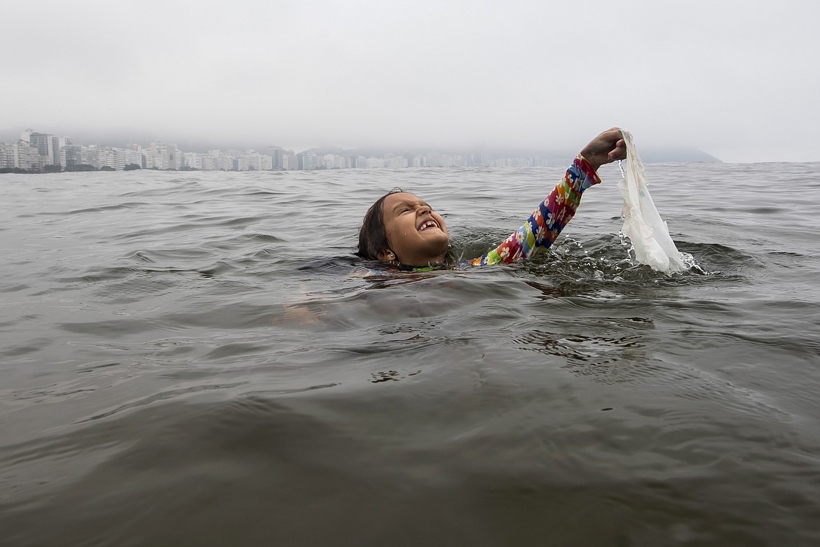 Nina Gomes recovers a discarded plastic bag from ocean waters, near Copacabana beach in Rio de Janeiro, Brazil, March 19, 2024. (AP Photo/Bruna Prado, File)