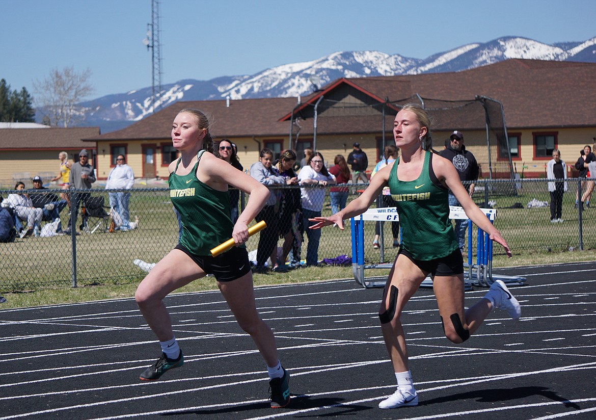 Whitefish sophomore Sage Boyes (left) receives the baton from junior Brynn Morse (right) during the 4X100 relay on Saturday. (Matt Weller photo)