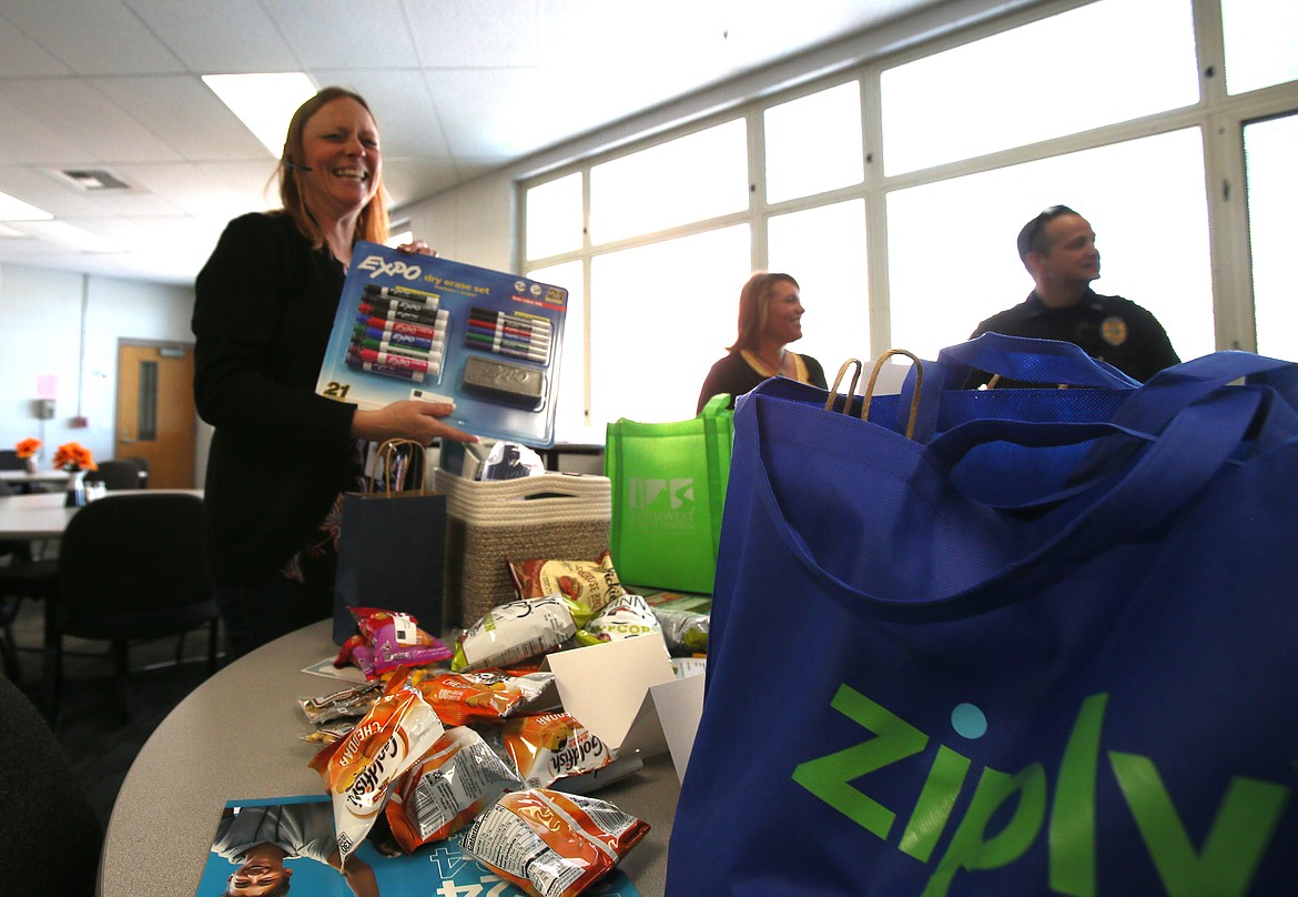 Bradi Zeigler, Post Falls High secretary, wears a big smile Tuesday morning as she unpacks baskets to set gifts on tables in the teachers' lounge after the Post Falls Chamber delivered goodies to thank teachers and school staff for all they do.