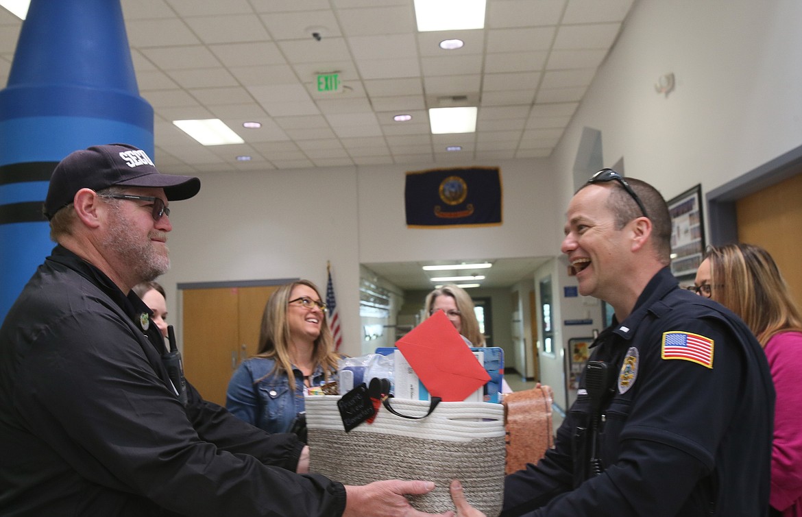 Post Falls Police Lt. Brian Harrison, right, hands Prairie View Elementary Safety Dean Rich Schutte a basket of gifts Tuesday morning.