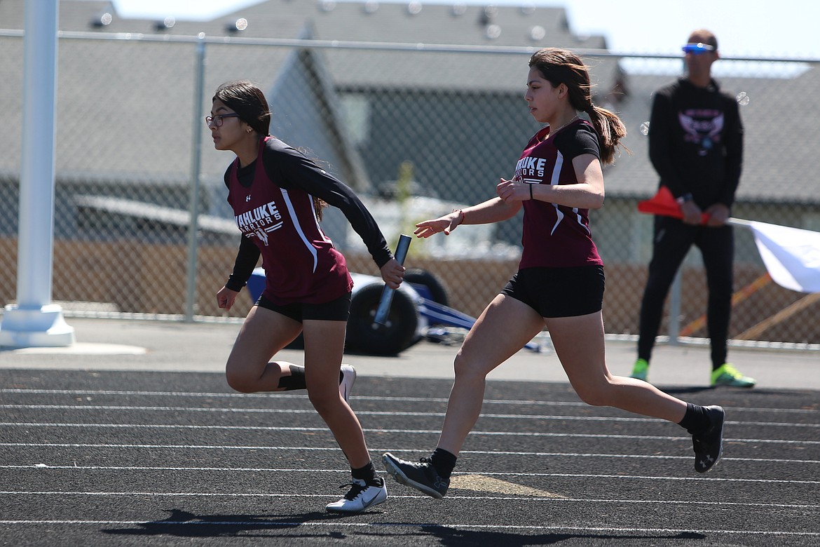 Wahluke sophomore Lorraine Badillo, right, passes the baton to sophomore Valerie Segura Espindole, left, during the girls 4x100-meter relay in Quincy.
