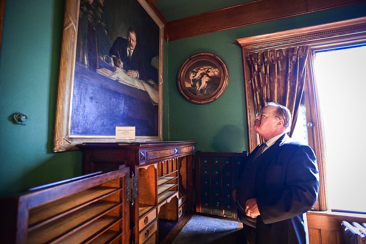 Impersonator Joe Wiegand portrays 26th U.S. President Theodore Roosevelt and admires a painting from 1922 titled "Theodore Roosevelt Seated at His Desk" by artist Adriaan De Groot during a tour of the Conrad Mansion in Kalispell on Wednesday, April 24. (Casey Kreider/Daily Inter Lake)