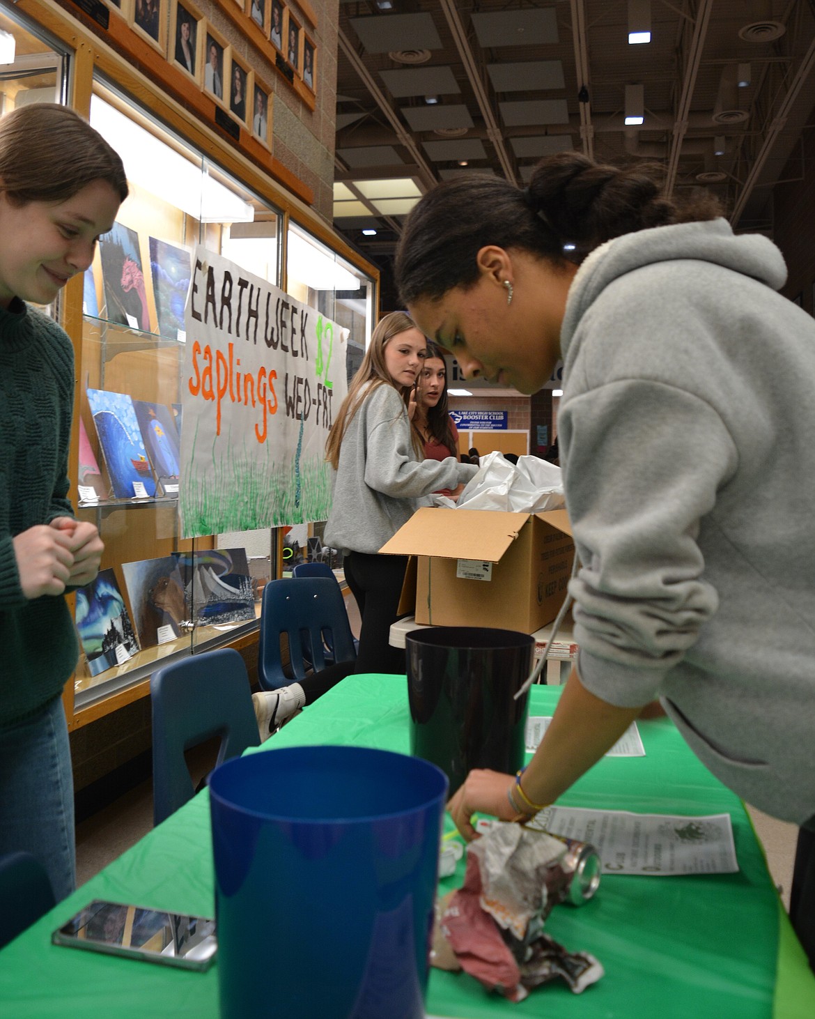 At the Lake City High School ecological club table, Gracie Ford watches as Nicole Ahrenholz demonstrates the timed recycling game the group came up with. Students have to sort through and identify which items are trash and which are recycling items in 10 seconds. If they get everything right, they receive a candy prize.